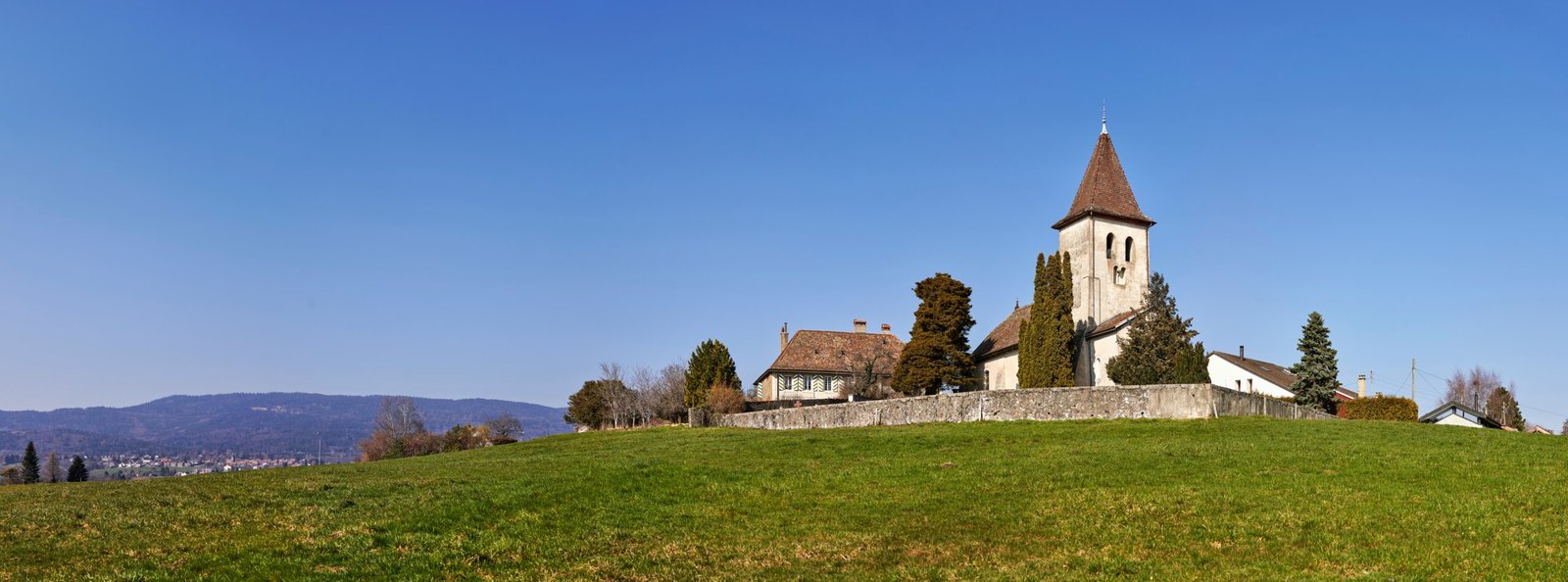 brown and white concrete house near green grass field under blue sky during daytime